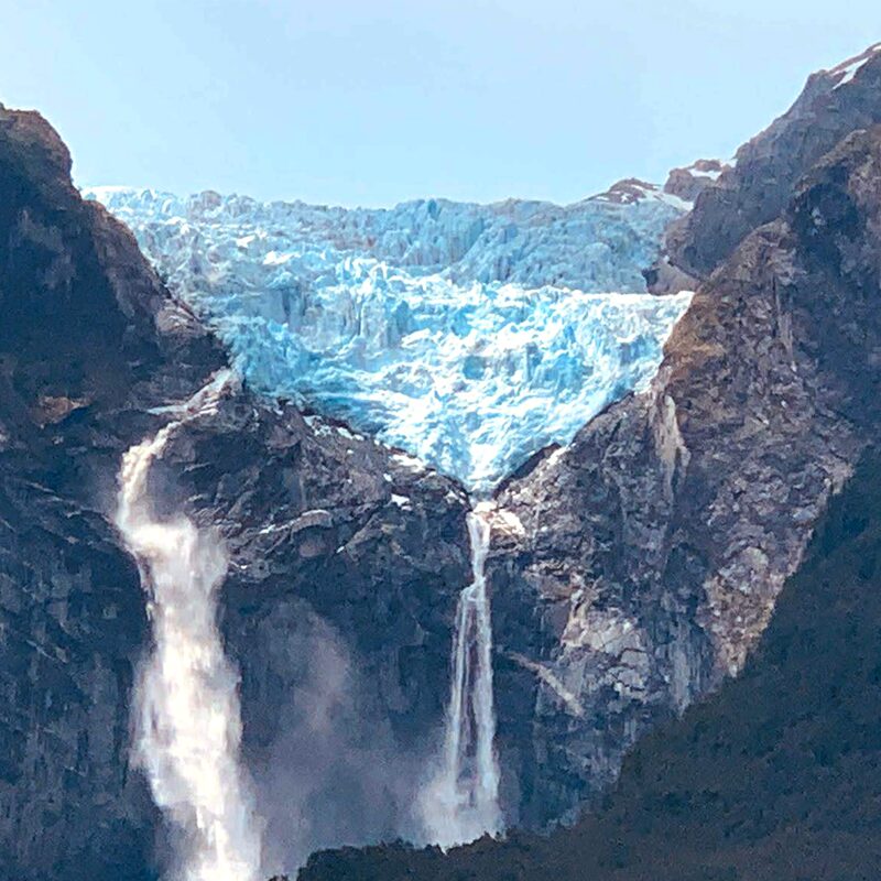 The stunning blue glacier and tall waterfall at Queulat National Park in Aysen, Patagonia