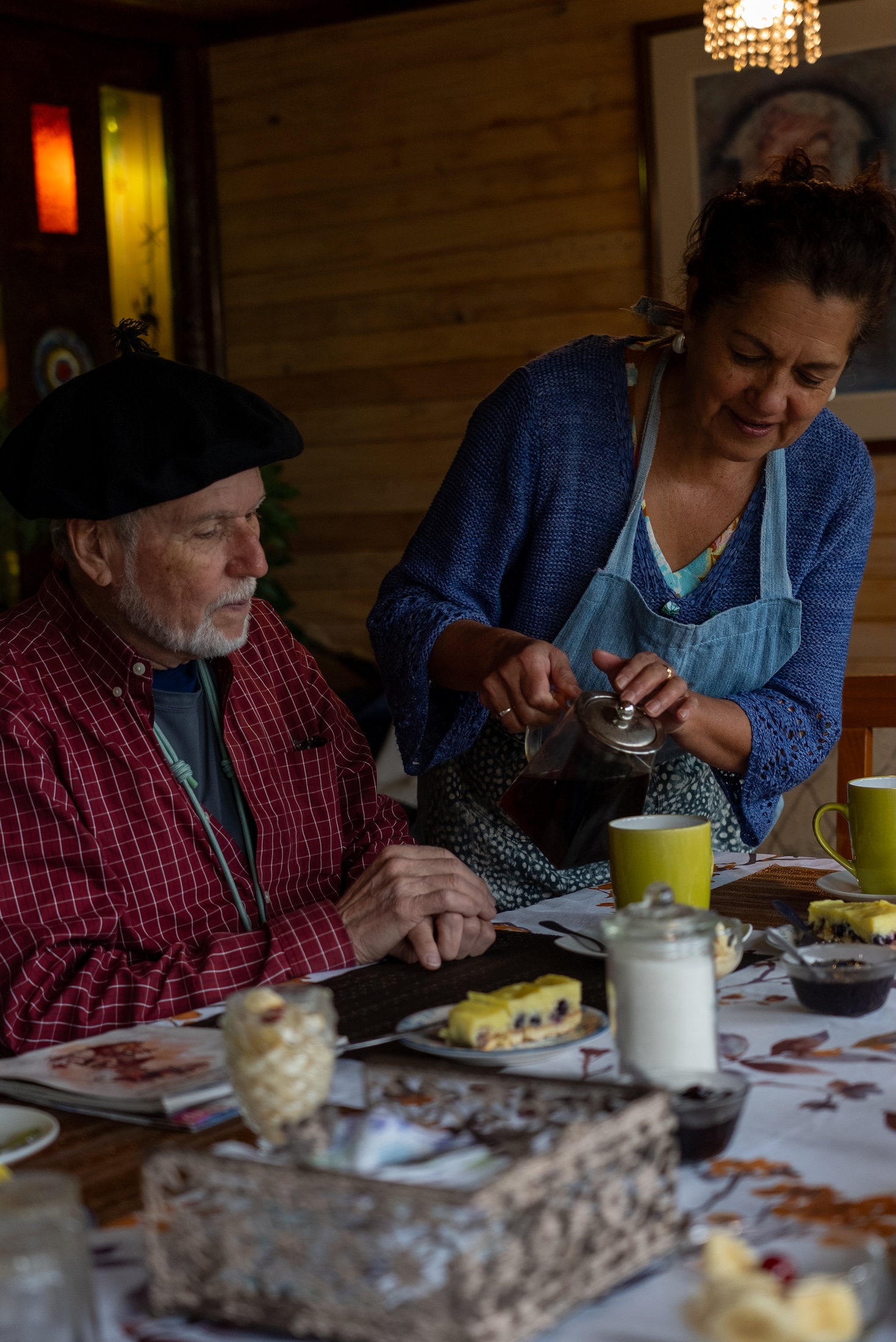 A person pours tea or coffee for a seated man at a table