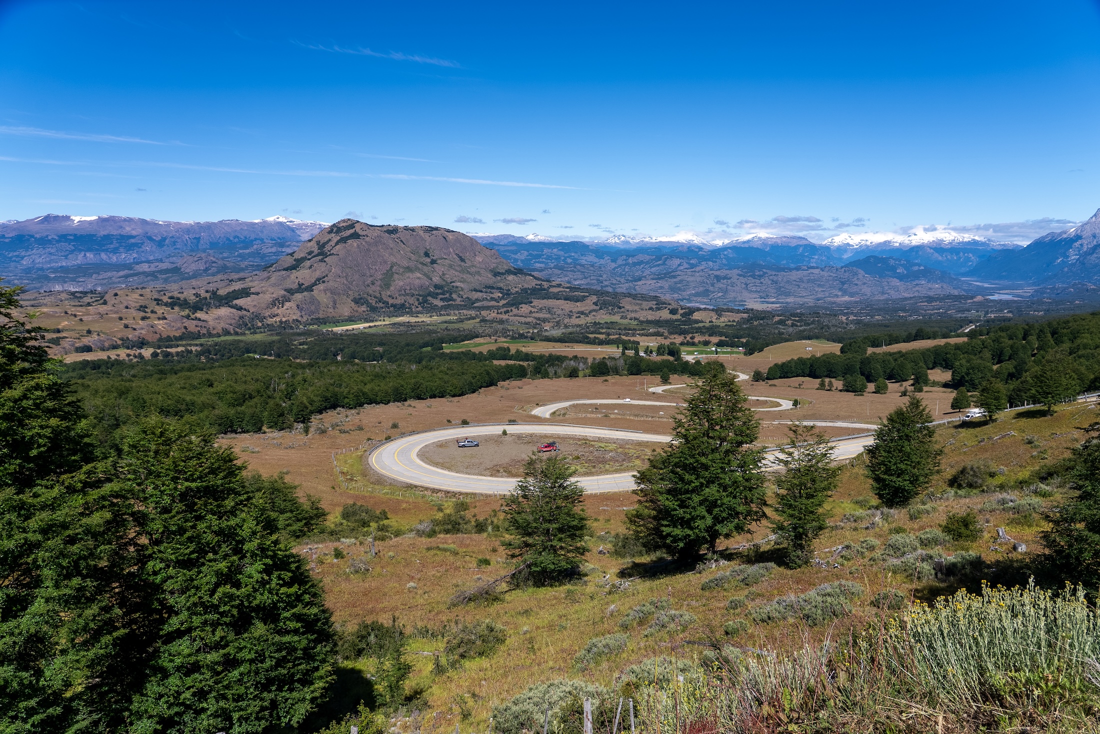 Three people in a hot tub look across the nearby lake towards mountains in the distance